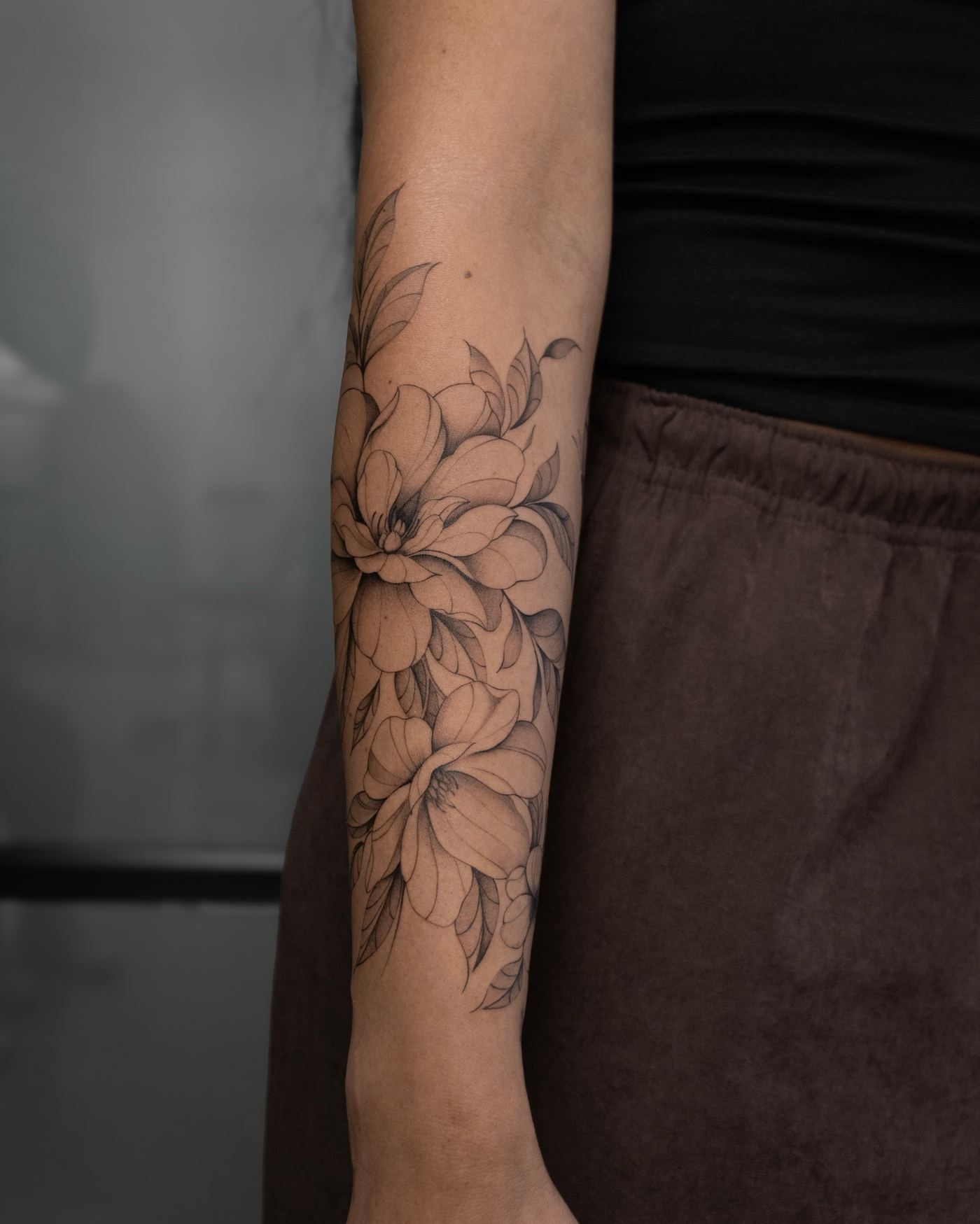 Fine line magnolia flower tattoo with soft shading, forearm